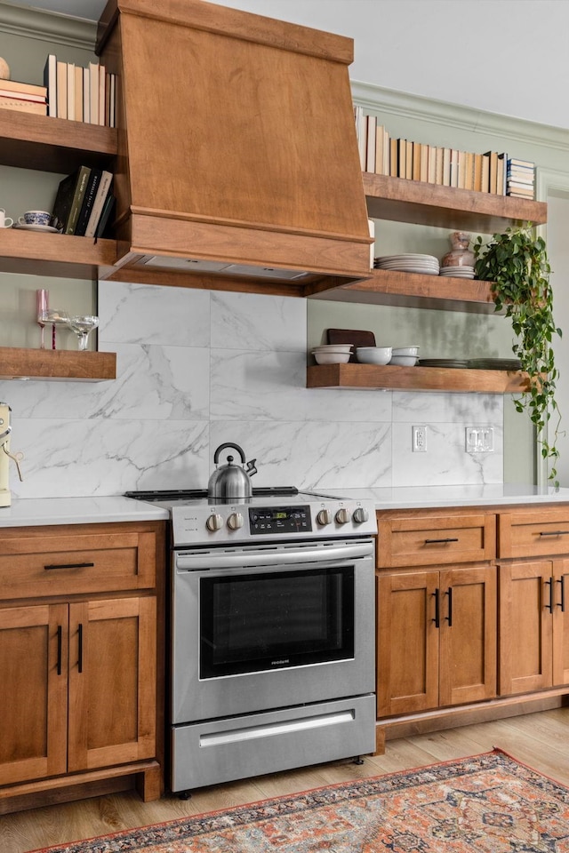 kitchen featuring backsplash, open shelves, stainless steel electric range, light countertops, and light wood-style flooring