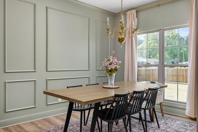 dining area featuring a notable chandelier, a wealth of natural light, wood finished floors, and a decorative wall