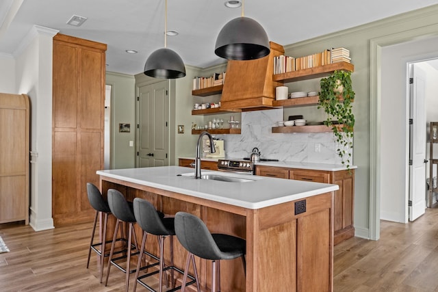 kitchen featuring crown molding, open shelves, a sink, light countertops, and light wood-style flooring