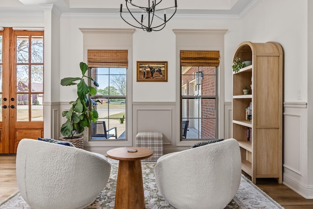 sitting room with crown molding, a wainscoted wall, a decorative wall, and a notable chandelier