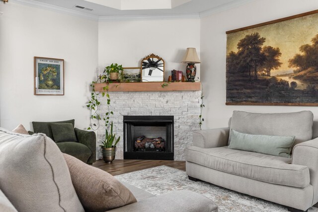 living area with crown molding, a fireplace, wood finished floors, and visible vents