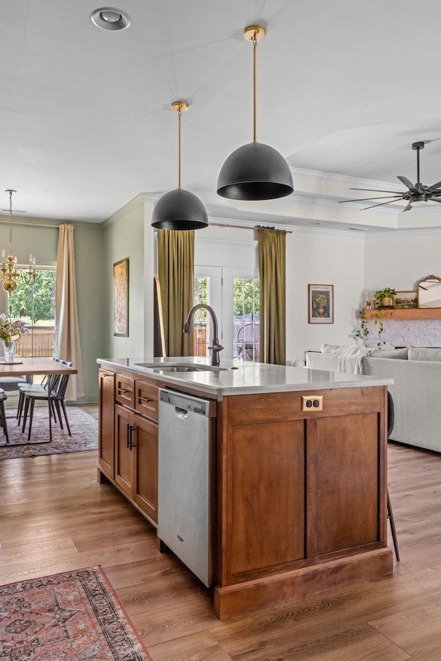kitchen with stainless steel dishwasher, a sink, crown molding, and a center island with sink
