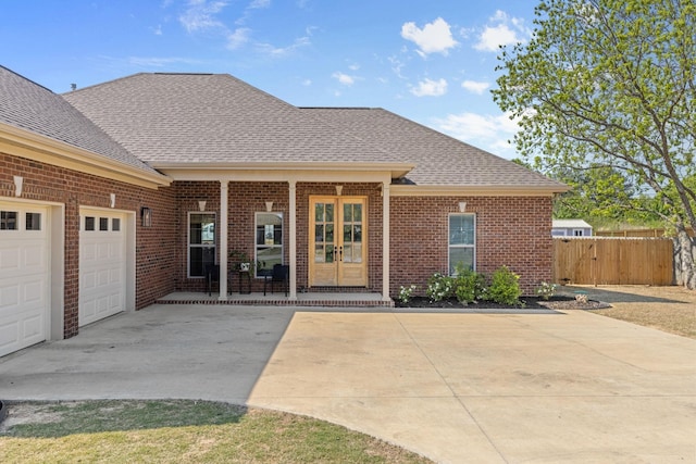 property entrance featuring fence, roof with shingles, brick siding, an attached garage, and driveway