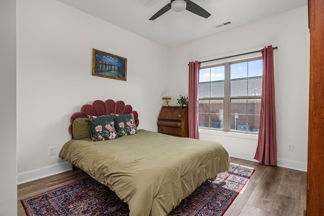 bedroom with baseboards, visible vents, and wood finished floors