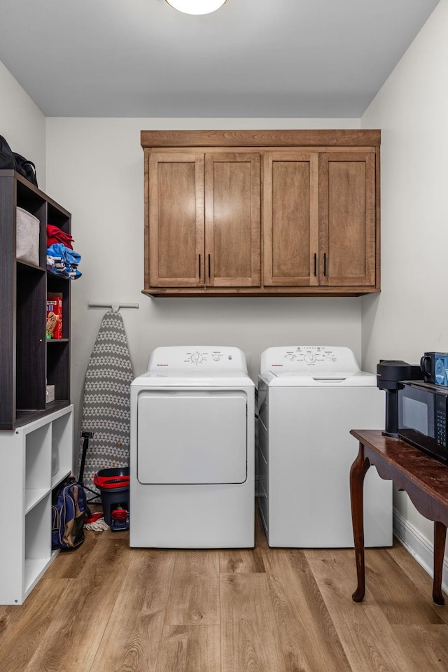 laundry room with independent washer and dryer, cabinet space, and light wood-type flooring