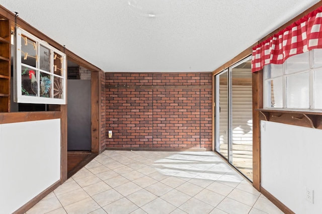 tiled empty room with brick wall and a textured ceiling