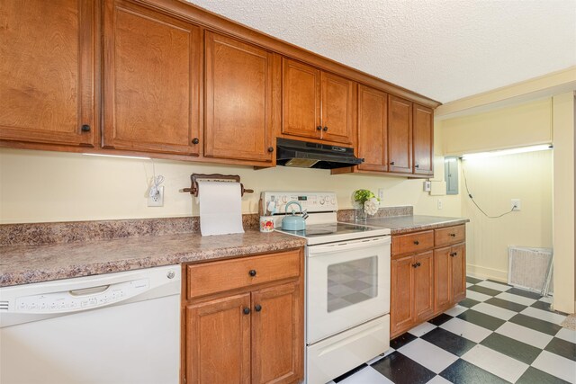  - kitchen with white appliances, under cabinet range hood, dark flooring, brown cabinetry, and a textured ceiling