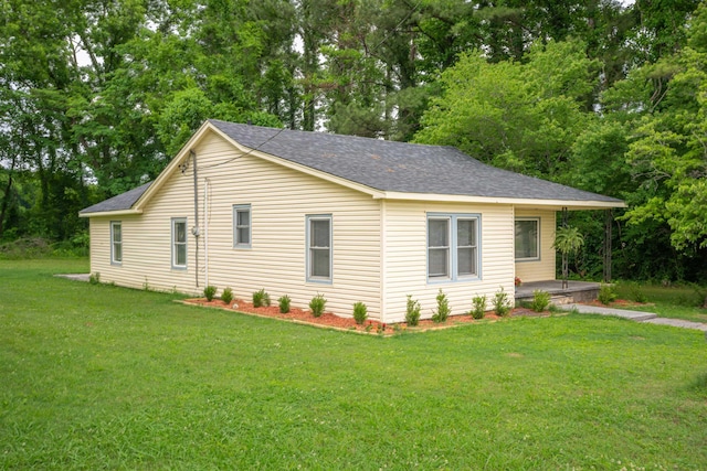  - view of side of property with a lawn, a shingled roof, and view of scattered trees