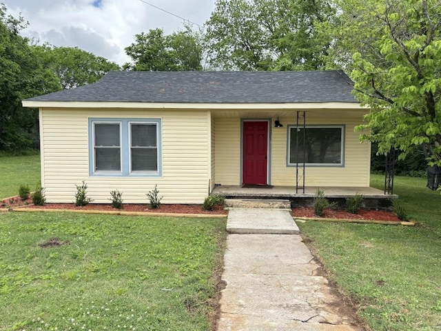 view of front of property featuring a front lawn, covered porch, and roof with shingles