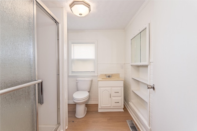 bathroom with wood finished floors, toilet, crown molding, a shower stall, and vanity