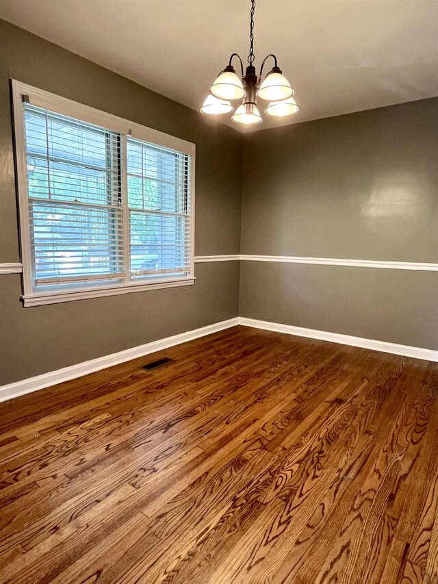 unfurnished room with hardwood / wood-style flooring and a notable chandelier