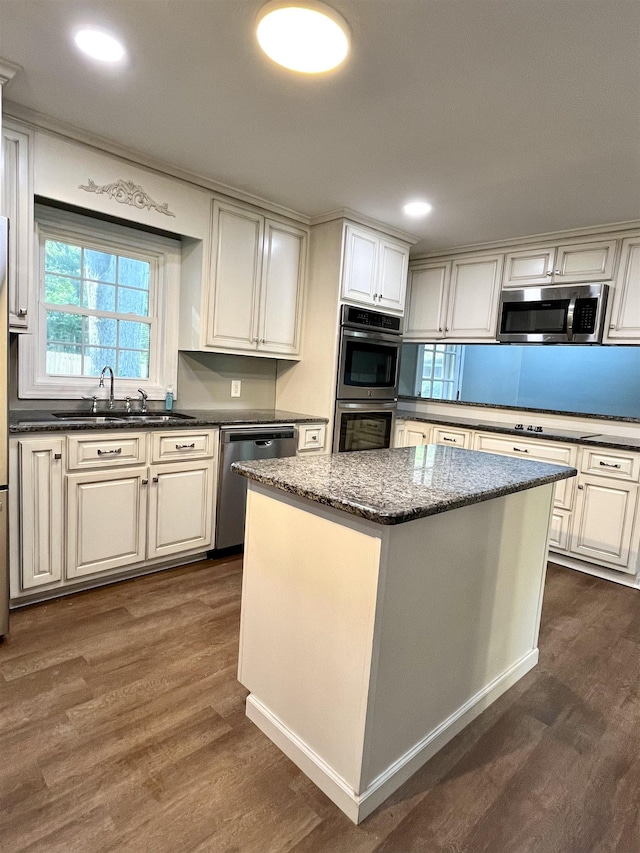 kitchen with a center island, sink, dark stone countertops, dark hardwood / wood-style flooring, and stainless steel appliances