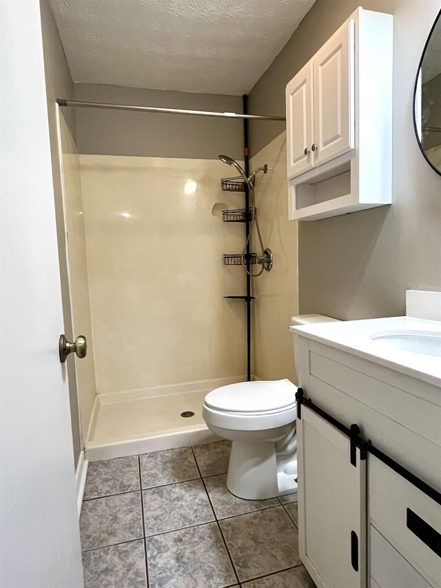 bathroom with vanity, a shower, tile patterned floors, toilet, and a textured ceiling