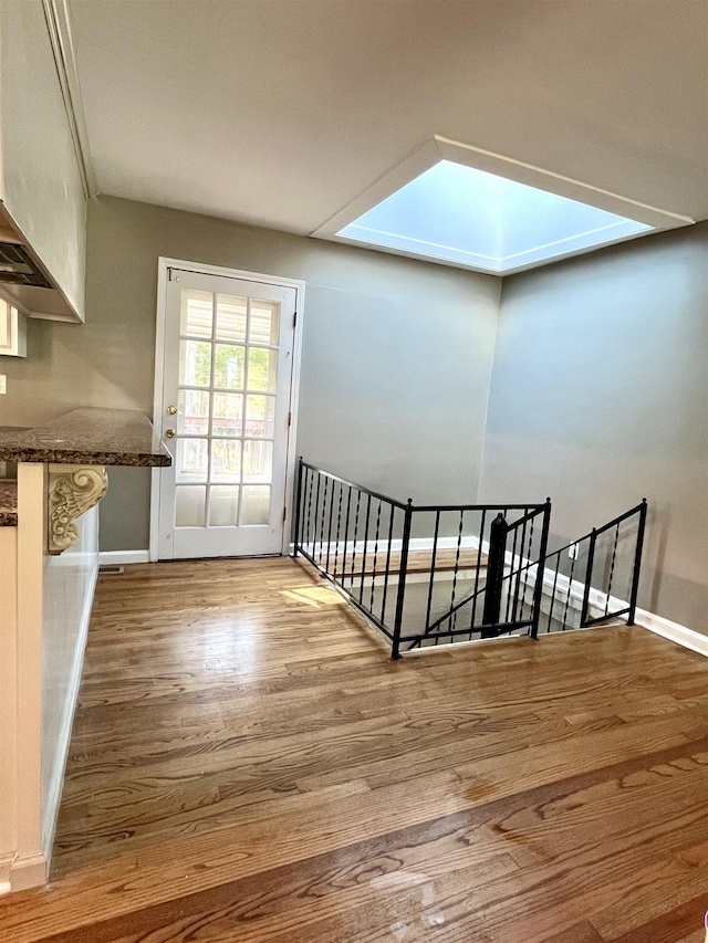 stairway with a skylight and hardwood / wood-style flooring