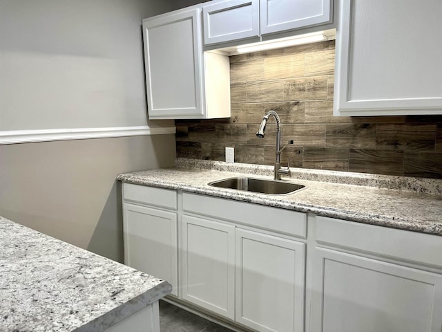 kitchen featuring tile patterned flooring, light stone counters, white cabinetry, and sink