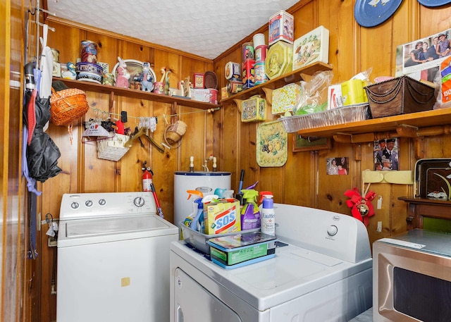 washroom with washer and dryer, gas water heater, and wood walls
