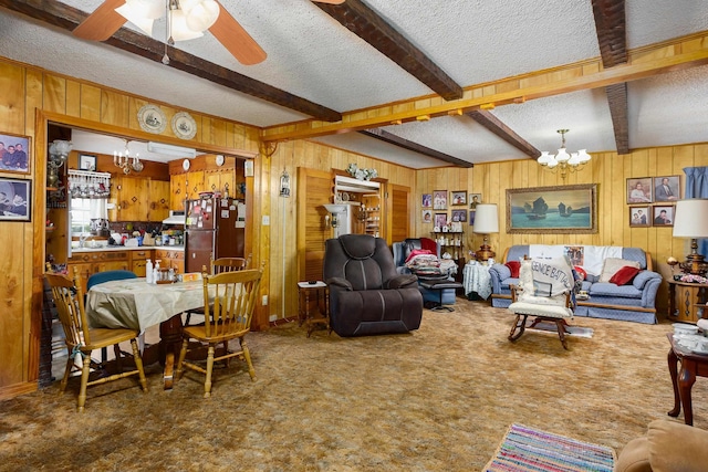 living area featuring a chandelier, wooden walls, a textured ceiling, beam ceiling, and a ceiling fan