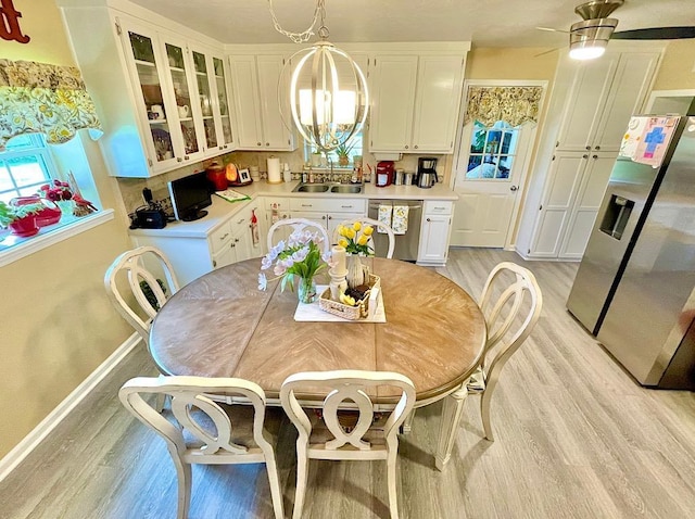 dining area featuring ceiling fan with notable chandelier, light hardwood / wood-style floors, and sink