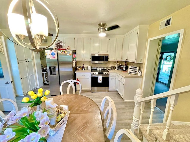 kitchen featuring ceiling fan, stainless steel appliances, tasteful backsplash, light hardwood / wood-style flooring, and white cabinets