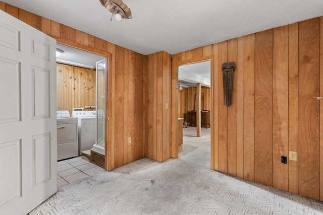 clothes washing area featuring wood walls, washer and clothes dryer, and a textured ceiling