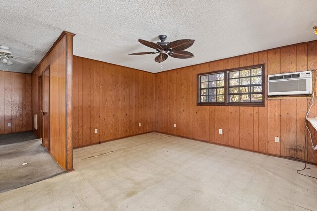 spare room with a wall mounted AC, wooden walls, and ceiling fan