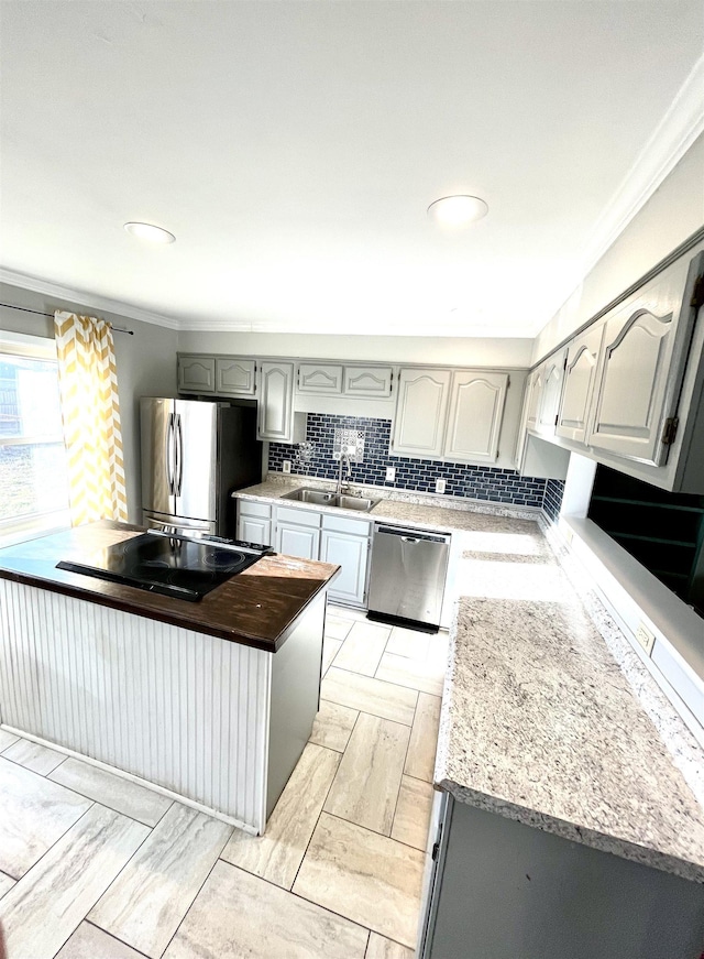 kitchen with a sink, stainless steel appliances, tasteful backsplash, and crown molding