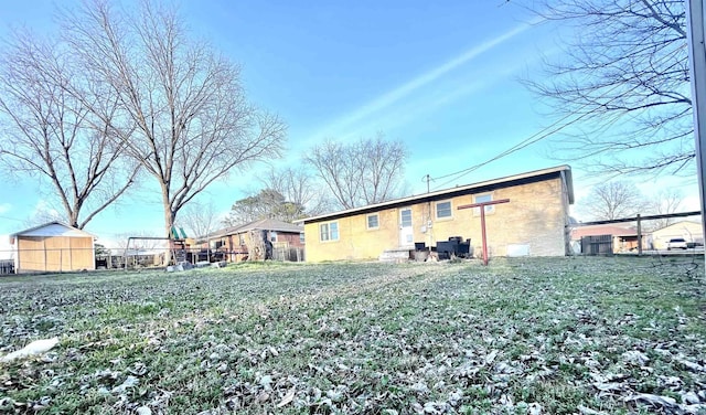 rear view of property featuring an outbuilding and fence