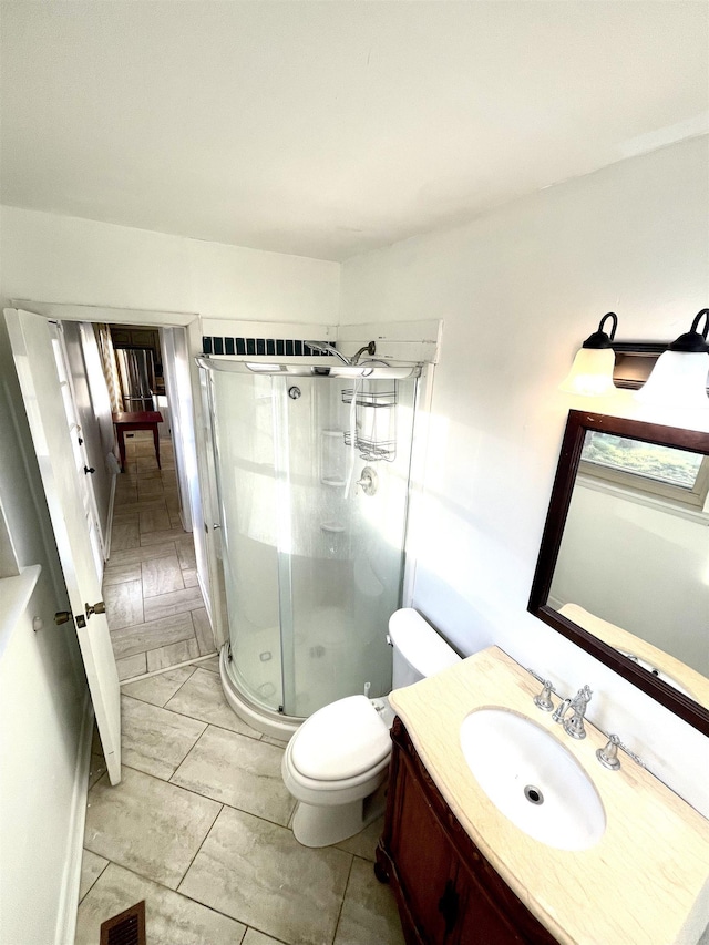 bathroom with vanity, a shower stall, toilet, and visible vents