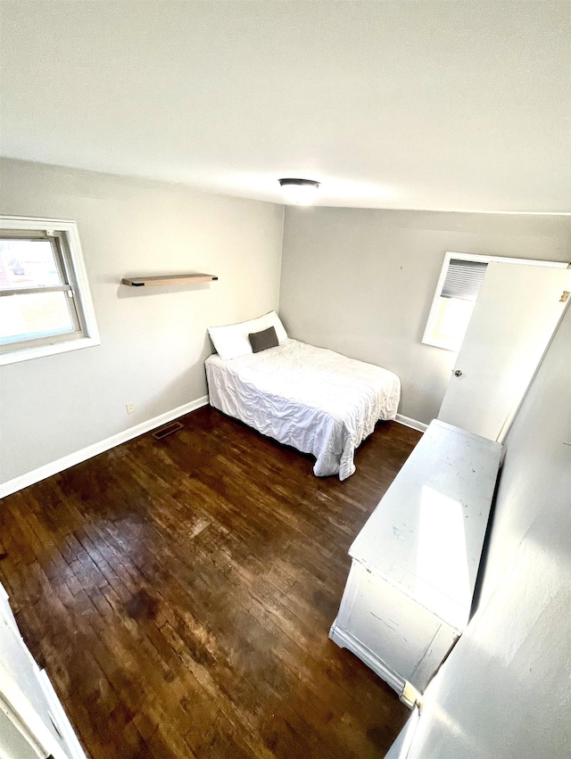 bedroom with visible vents, baseboards, and wood finished floors