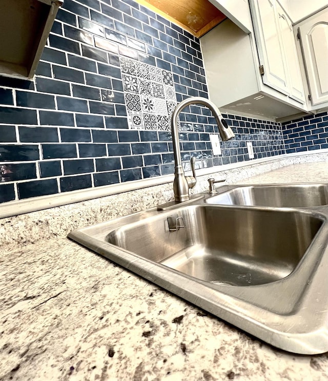 details with a sink, decorative backsplash, and white cabinetry