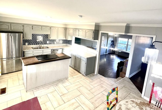 kitchen with gray cabinetry, a sink, appliances with stainless steel finishes, crown molding, and decorative backsplash