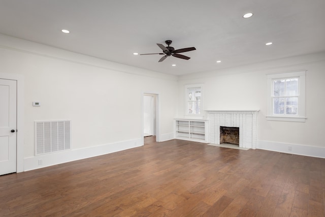 unfurnished living room featuring ceiling fan, a fireplace, ornamental molding, and dark hardwood / wood-style floors