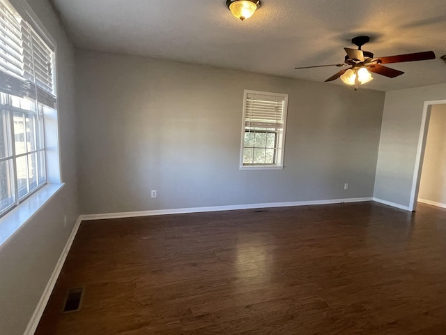 spare room with ceiling fan, a wealth of natural light, and dark hardwood / wood-style flooring