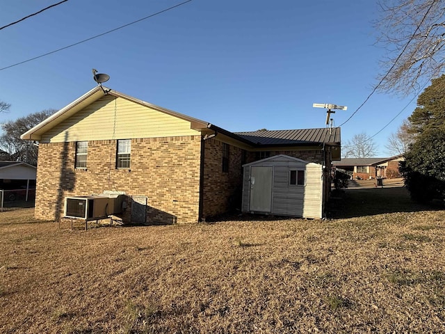 back of house with central AC unit, a yard, and a storage unit