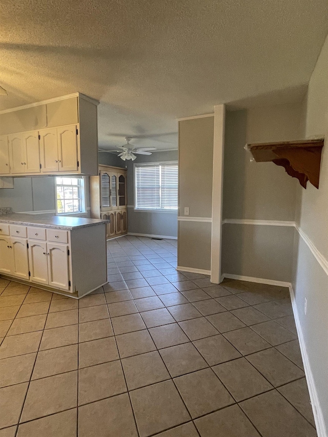 kitchen with ceiling fan, white cabinetry, plenty of natural light, and light tile patterned flooring