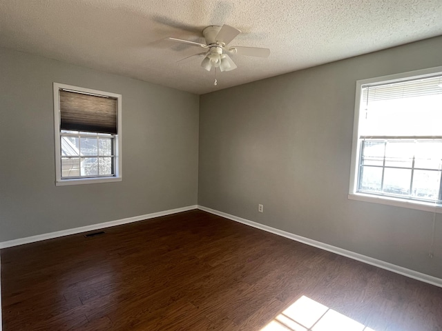 unfurnished room featuring ceiling fan, dark wood-type flooring, and a wealth of natural light