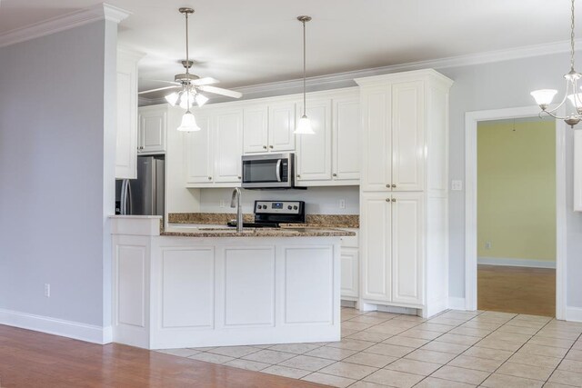 kitchen with crown molding, white cabinets, stainless steel appliances, and ceiling fan with notable chandelier