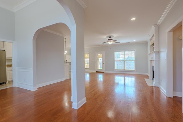 unfurnished living room featuring ceiling fan, light hardwood / wood-style floors, and ornamental molding