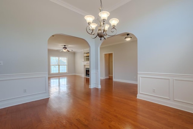 interior space featuring ceiling fan with notable chandelier, wood-type flooring, and crown molding