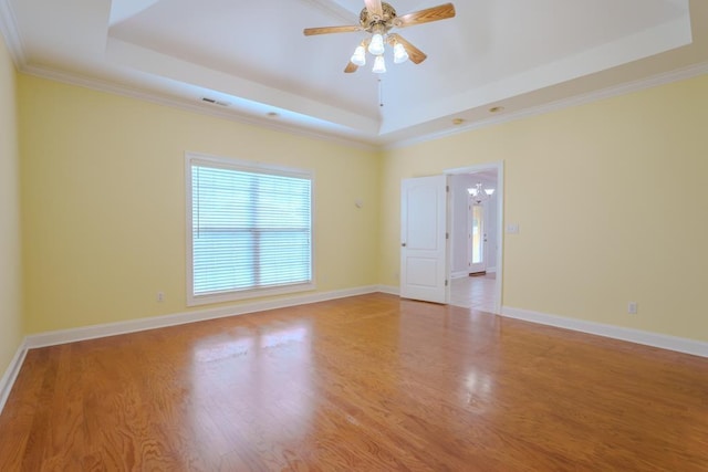 empty room with ceiling fan with notable chandelier, a raised ceiling, light wood-type flooring, and ornamental molding