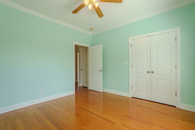 unfurnished bedroom featuring ceiling fan, a closet, light wood-type flooring, and ornamental molding