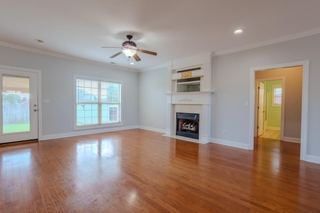 unfurnished living room with built in shelves, hardwood / wood-style flooring, ceiling fan, and crown molding