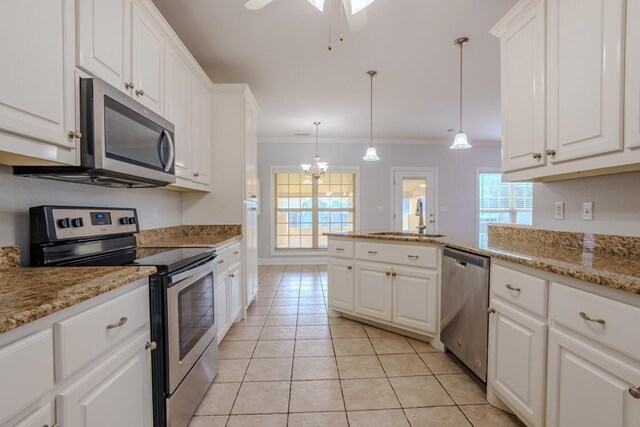 kitchen featuring pendant lighting, white cabinets, sink, ornamental molding, and stainless steel appliances