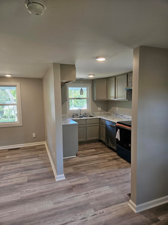 kitchen with pendant lighting, black appliances, sink, light hardwood / wood-style flooring, and gray cabinets