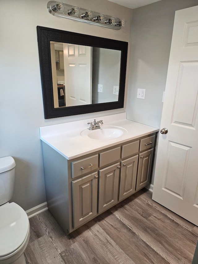 bathroom with hardwood / wood-style floors, vanity, and toilet