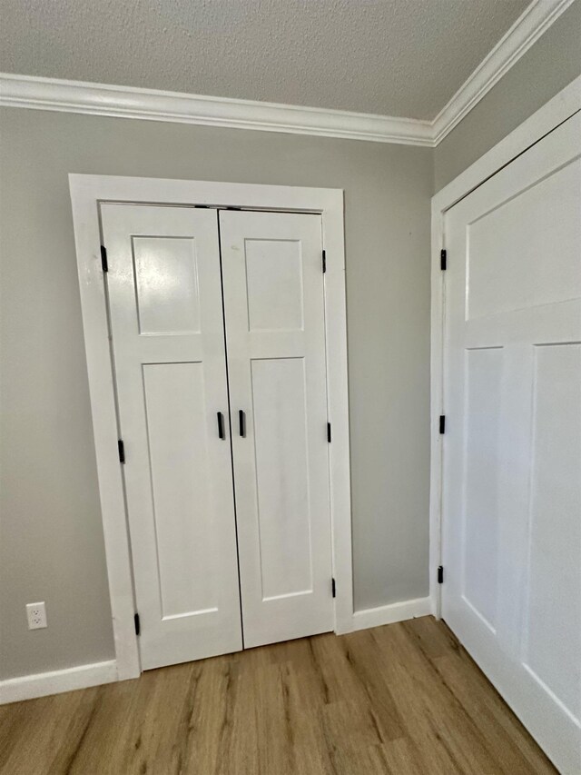 interior space featuring crown molding, wood-type flooring, and a textured ceiling