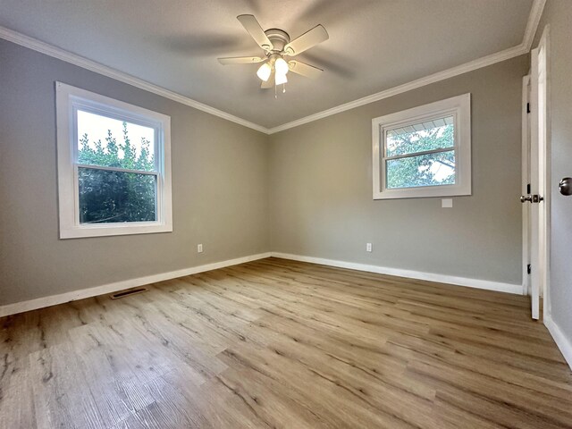 empty room with crown molding, plenty of natural light, ceiling fan, and light wood-type flooring