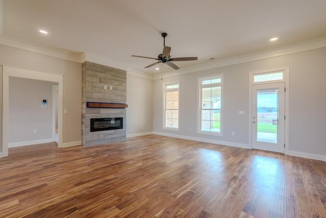 unfurnished living room featuring a tile fireplace, light wood-type flooring, crown molding, and ceiling fan