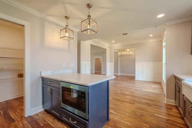 kitchen featuring crown molding, hardwood / wood-style flooring, light stone countertops, built in microwave, and decorative light fixtures