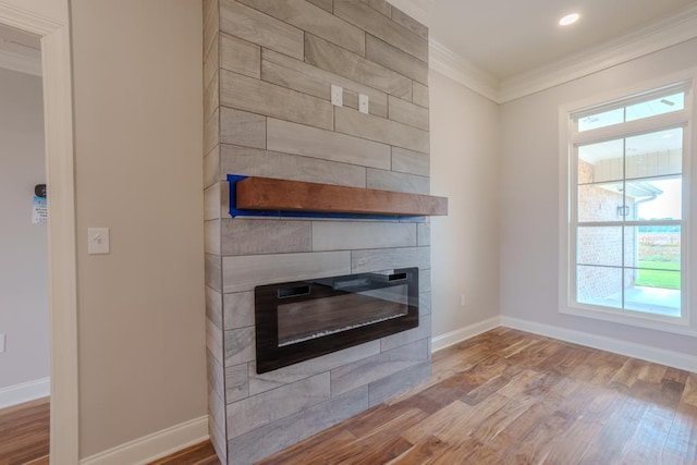 unfurnished living room featuring light hardwood / wood-style flooring, crown molding, a fireplace, and a healthy amount of sunlight